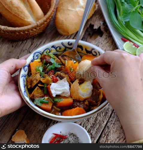 Vietnam food, bread with stewed beef, a popular meal at morning, eat attach parsley, basil, lemon pepper and salt make so delicious taste