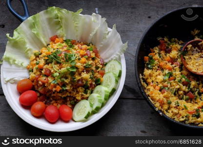 Vietnam food, fried rice, make from rice, egg, sausage, dried shrimp, bean, cucumber, tomato, carrot and scallion, high view of dishl on wooden background