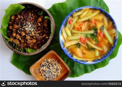 Vietnamese cuisine from red rice, delicious and nutrition rice dish for lunch, homemade food rich nutritious in coconut shell bowl with sesame salt on green leaf background