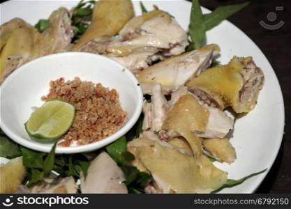 Vietnamese food, boiled chicken plate with pepper and salt, serve with laksa leaves and lemon