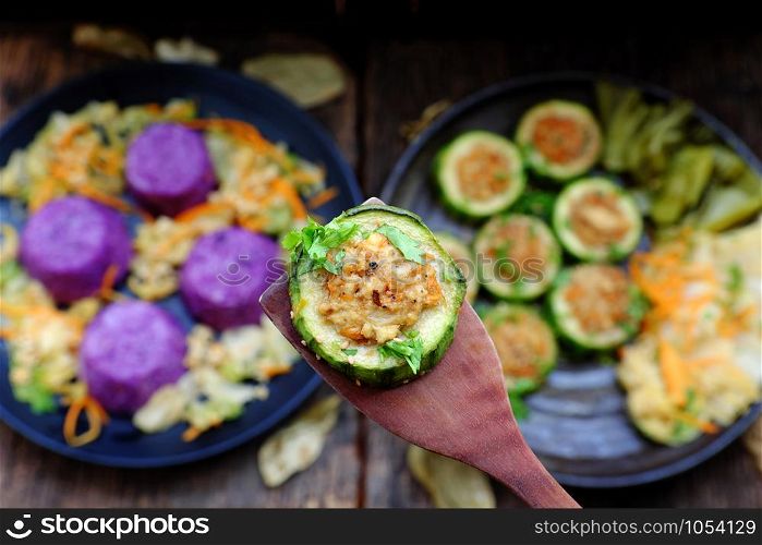 Vietnamese homemade vegetarian eating on black plate, grilled vegetables with slice of winter melon stuff with tofu, carrot, rice dish in violet, delicious vegan meal that frugal, healthy