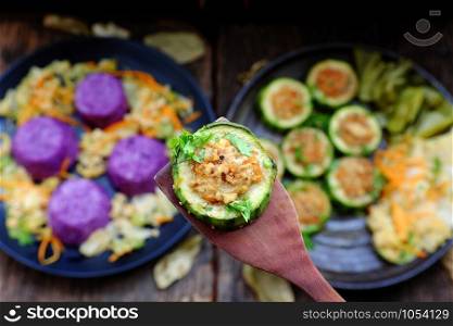 Vietnamese homemade vegetarian eating on black plate, grilled vegetables with slice of winter melon stuff with tofu, carrot, rice dish in violet, delicious vegan meal that frugal, healthy
