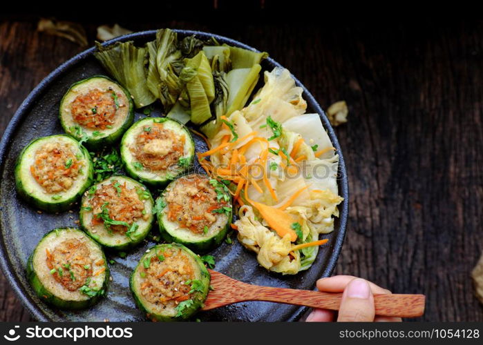 Vietnamese homemade vegetarian eating on black plate on wooden background, grilled vegetables with slice of winter melon stuff with tofu and carrot, delicious vegan meal that frugal, healthy.