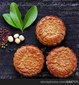 Vietnamese sweet food for mid autumn festival when full moon, moon cake from top view on black wooden background, delicious homemade mooncake of Vietnam cuisine culture