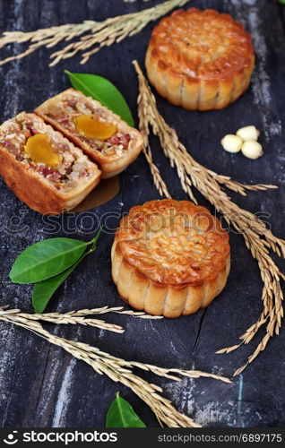 Vietnamese sweet food for mid autumn festival when full moon, moon cake from top view on black wooden background, delicious homemade mooncake of Vietnam cuisine culture