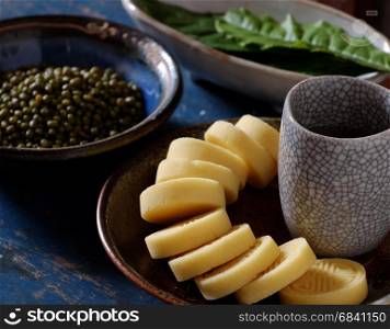 Vietnamese sweet food, green beans cake from green lentils, a traditional food for tea time, plate of food, cup of tea on wood background