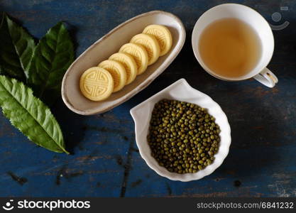 Vietnamese sweet food, green beans cake from green lentils, a traditional food for tea time, plate of food, cup of tea on wood background