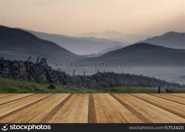 View along misty valley towards Snowdonia mountains. View along countryside fields towards misty Snowdonia mountain range in distance with wooden planks floor