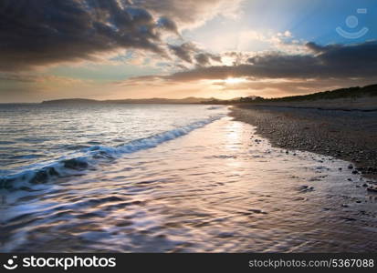 View along West coast of Wales towards beautiful sunset with sunbeams and stunning clouds formations