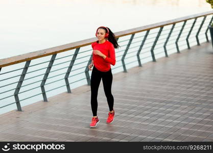 View at active young beautiful woman running on the promenade along the river  side