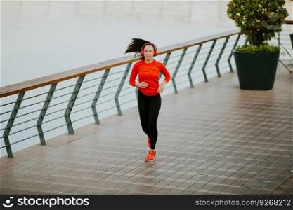 View at active young beautiful woman running on the promenade along the river  side
