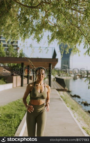 View at active young beautiful woman running on the promenade along the riverside