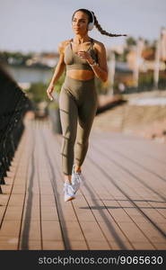 View at active young beautiful woman running on the promenade along the riverside