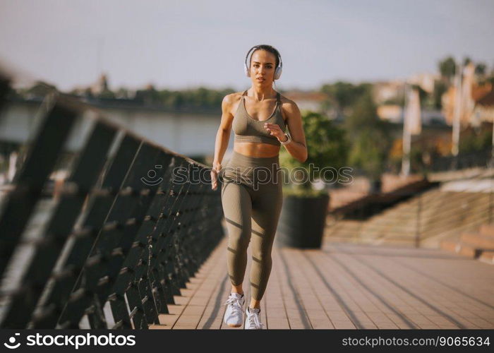 View at active young beautiful woman running on the promenade along the riverside