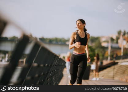 View at active young beautiful woman running on the promenade along the riverside