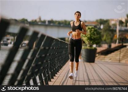 View at active young beautiful woman running on the promenade along the riverside