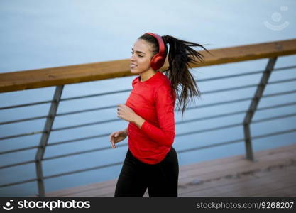 View at active young beautiful woman running on the promenade along the riverside