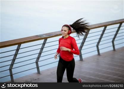 View at active young beautiful woman running on the promenade along the riverside
