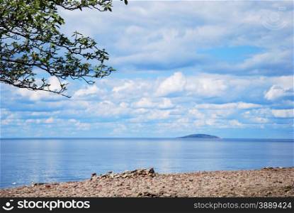 View at an blue island from a stony coast with calm water in Sweden