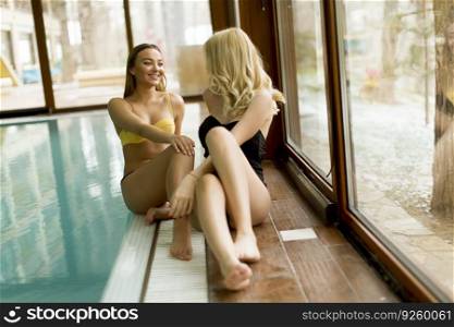 View at beautiful young women relaxing by swimming pool in the spa