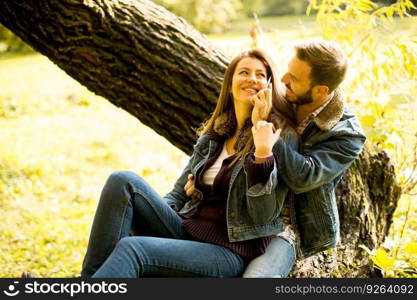 View at Couple in love sitting on a tree in autumn park