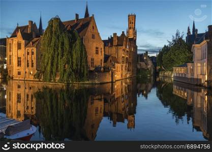 View at dusk of the Rozenhoedkaai in the city of Bruges in Belgium, with the Belfry in the background. The historic city center is a UNESCO World Heritage Site.