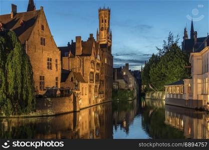 View at dusk of the Rozenhoedkaai in the city of Bruges in Belgium, with the Belfry in the background. The historic city center is a UNESCO World Heritage Site