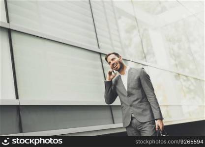 View at handsome young businessman with mobile phone by the office building