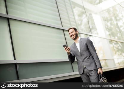 View at handsome young businessman with mobile phone by the office building