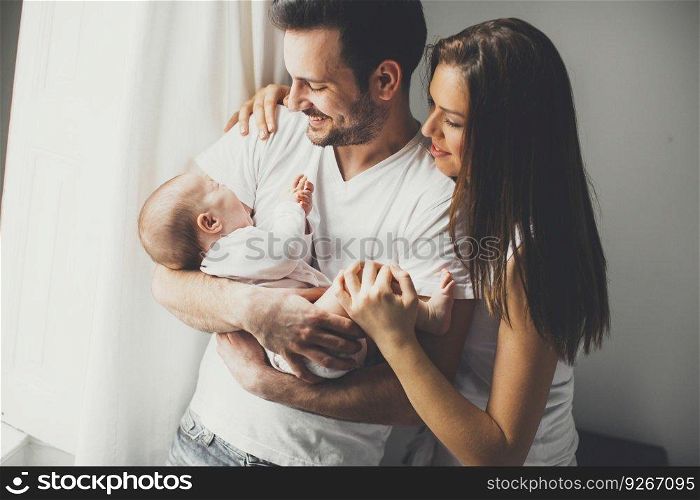 View at Happy family with newborn baby by the window