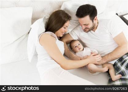 View at happy family with newborn baby on the bed in room