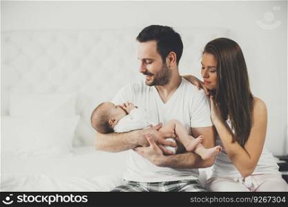 View at happy family with newborn baby on the bed in room