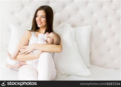 View at happy mother with baby on bed