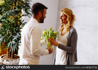View at man giving bouquet of yellow tulips to  his girlfriend