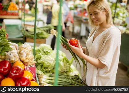 View at pretty young woman buying vegetables at the market