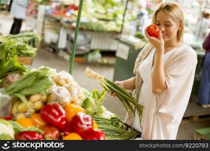 View at pretty young woman buying vegetables at the market
