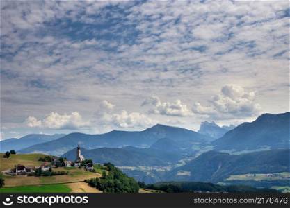 View at the Saint Nikolaus church in Mittelberg in the municipality Ritten in South Tyrol with the Dolomites mountain tops in the background. View at the Saint Nikolaus church in Mittelberg