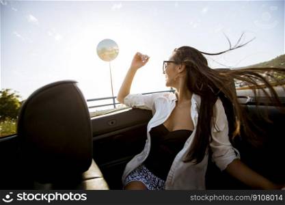 View at young attractive woman drive in cabriolet at seaside
