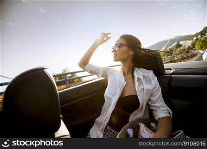 View at young attractive woman drive in cabriolet at seaside