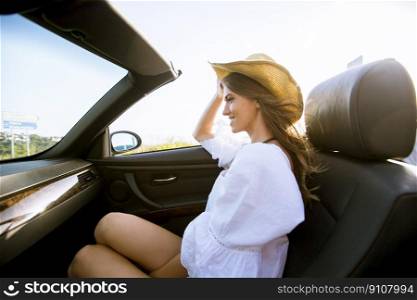 View at young attractive woman driving in cabriolet at seaside