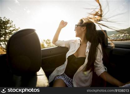 View at young attractive woman poses in  cabriolet at seaside