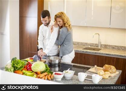 View at young man helping his girlfriend cooking in modern kitchen