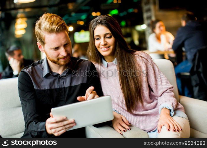 View at young modern couple sitting together and using a tablet