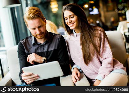 View at young modern couple sitting together and using a tablet