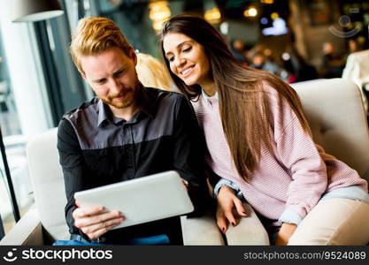 View at young modern couple sitting together and using a tablet