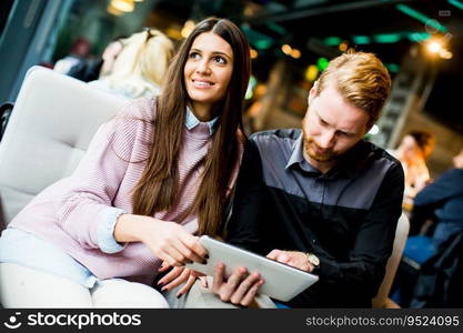 View at young modern couple sitting together and using a tablet