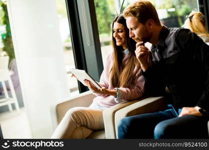 View at young modern couple sitting together and using a tablet