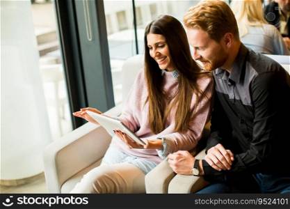 View at young modern couple sitting together and using a tablet