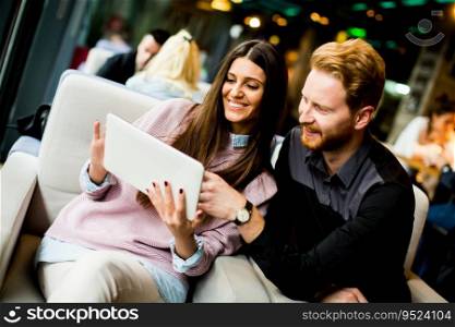 View at young modern couple sitting together and using a tablet