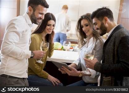 View at young people looking at digital tablet with white wine in the kitchen